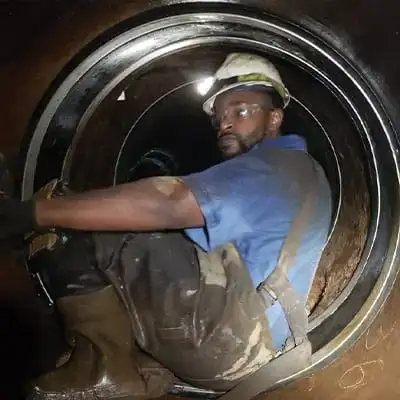 A technician sitting in a water main atop a HydraTite seal