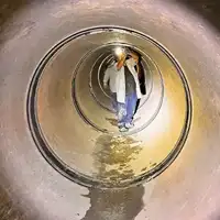 A technician installing HydraTite over a joint using a headlamp to see inside the pipe