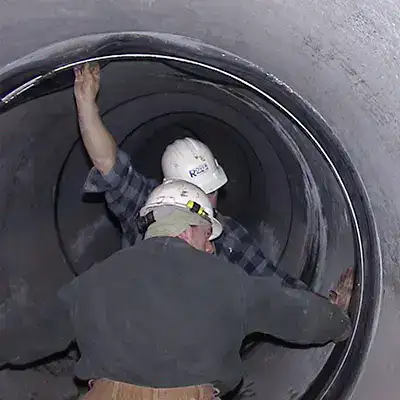 HydraTite being positioned over a joint in a pipe by two technicians