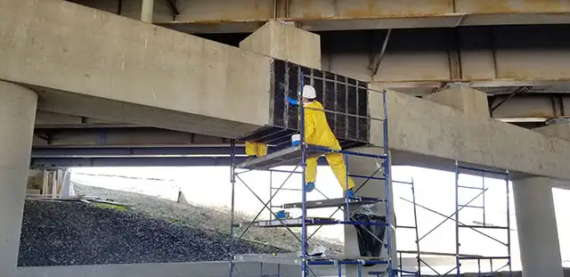 A technician applying fiber wrap to a bridge support