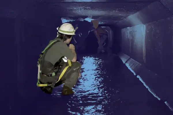 A technician sitting in a box-shaped culvert
