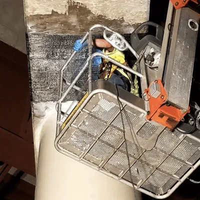 Carbon fiber fabric being applied by a technician in a lift to strengthen a bridge's supports