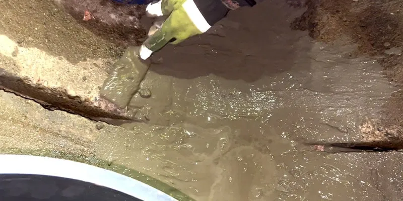 Concrete being applied to the invert of a pipe near a joint