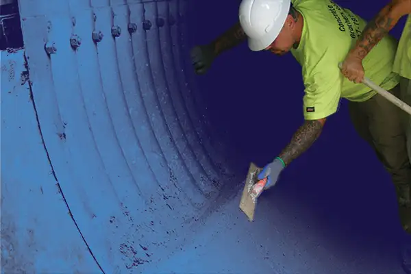 A technician smoothing out the concrete along the invert of a corrugated metal pipe