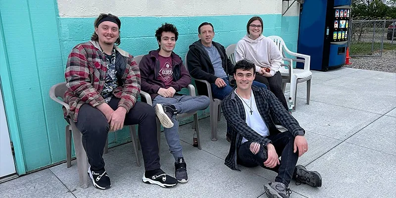 A group of employees sitting outside of a Holiday Auto Theatre