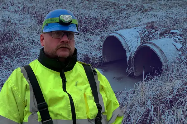 A technician standing in front of a twin culvert entrance
