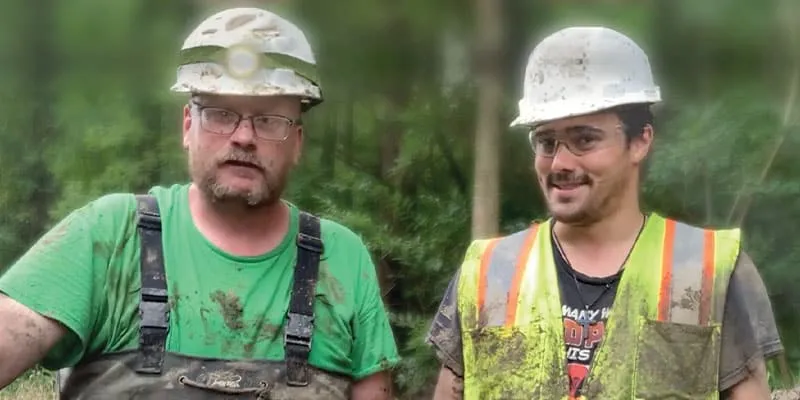 Two technicians standing near a culvert they just worked in