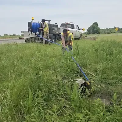 Several people cleaning out a culvert with a jetter vac