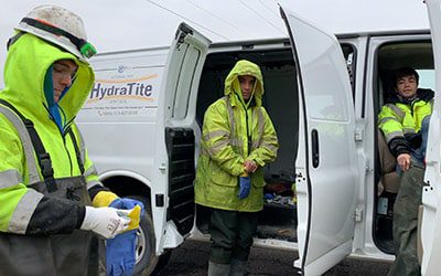 Three field services crew members preparing to enter a pipe