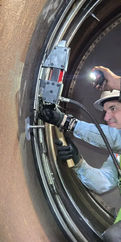 A person using an expander to install HydraTite over a joint inside a penstock pipe